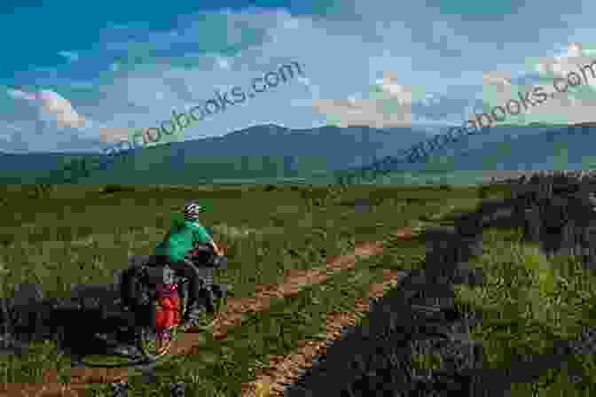 A Cyclist Riding Through A Field With A Vast Sky And Distant Mountains On The Northern Tier Bicycle Route Cycling In Northern Ontario Thomas E Alexander